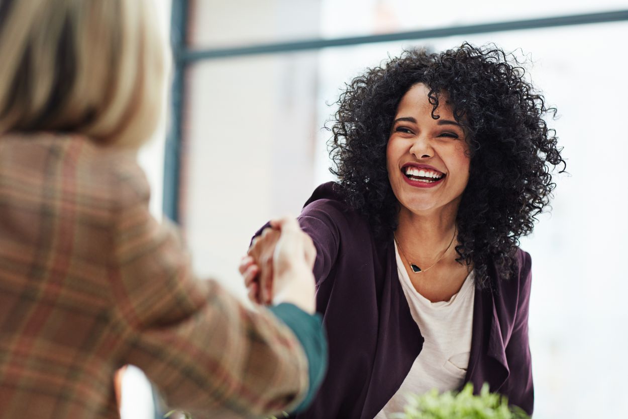 Two smiling business women shake hands