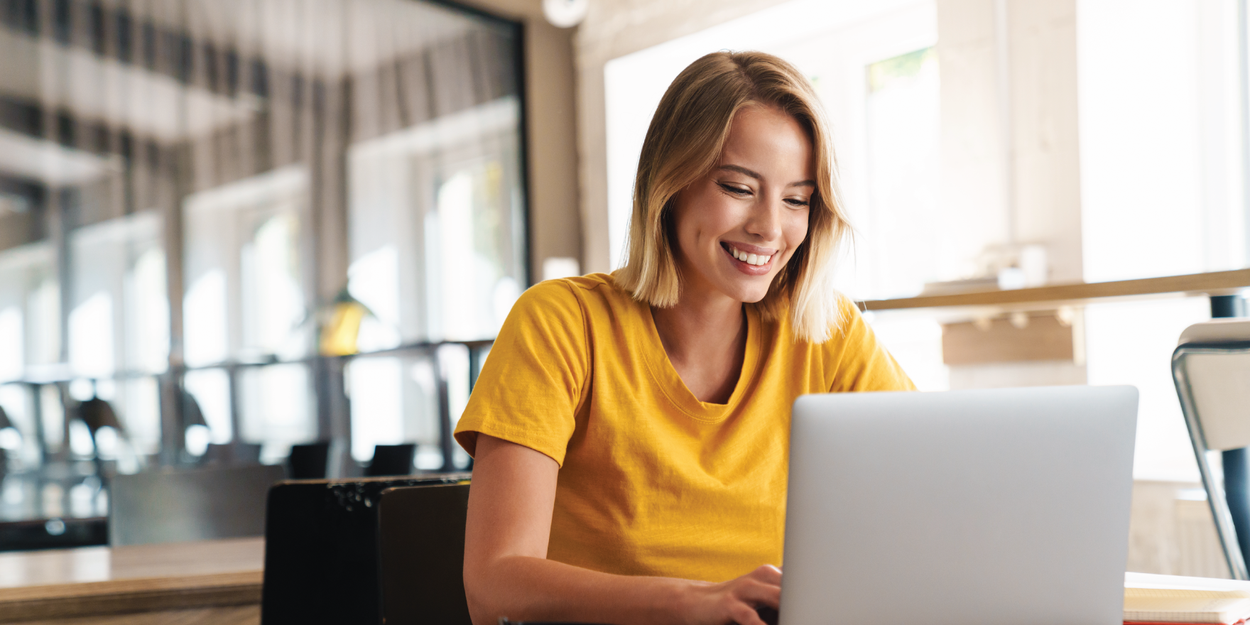 Woman in yellow shirt looking at her laptop