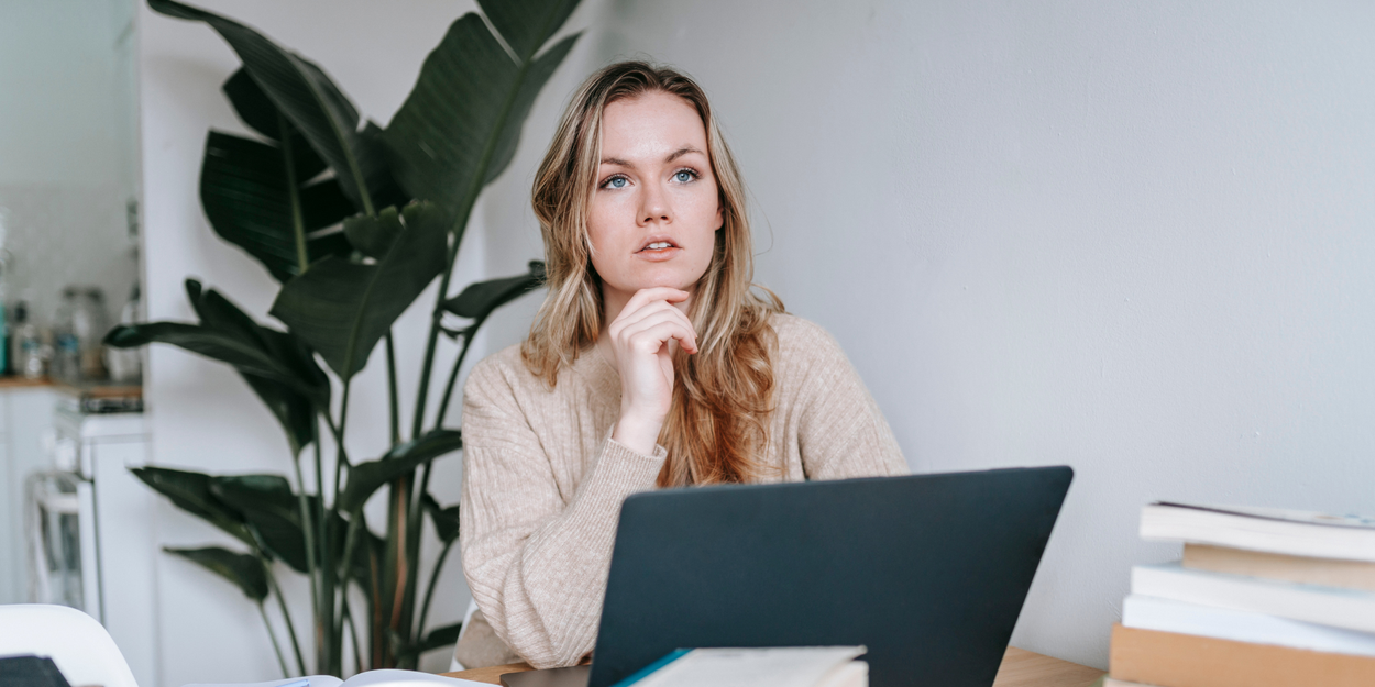 Woman with blond hair at desk thinking